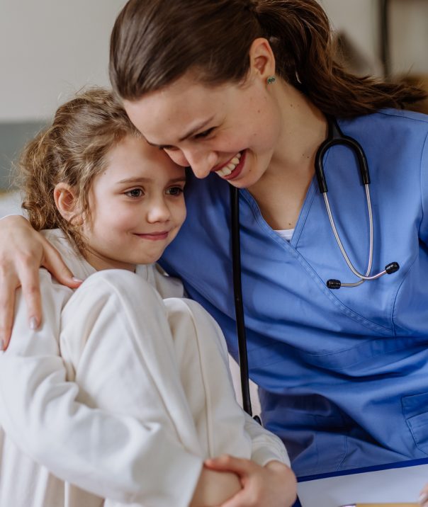 Young doctor consoling little girl in a hospital room.